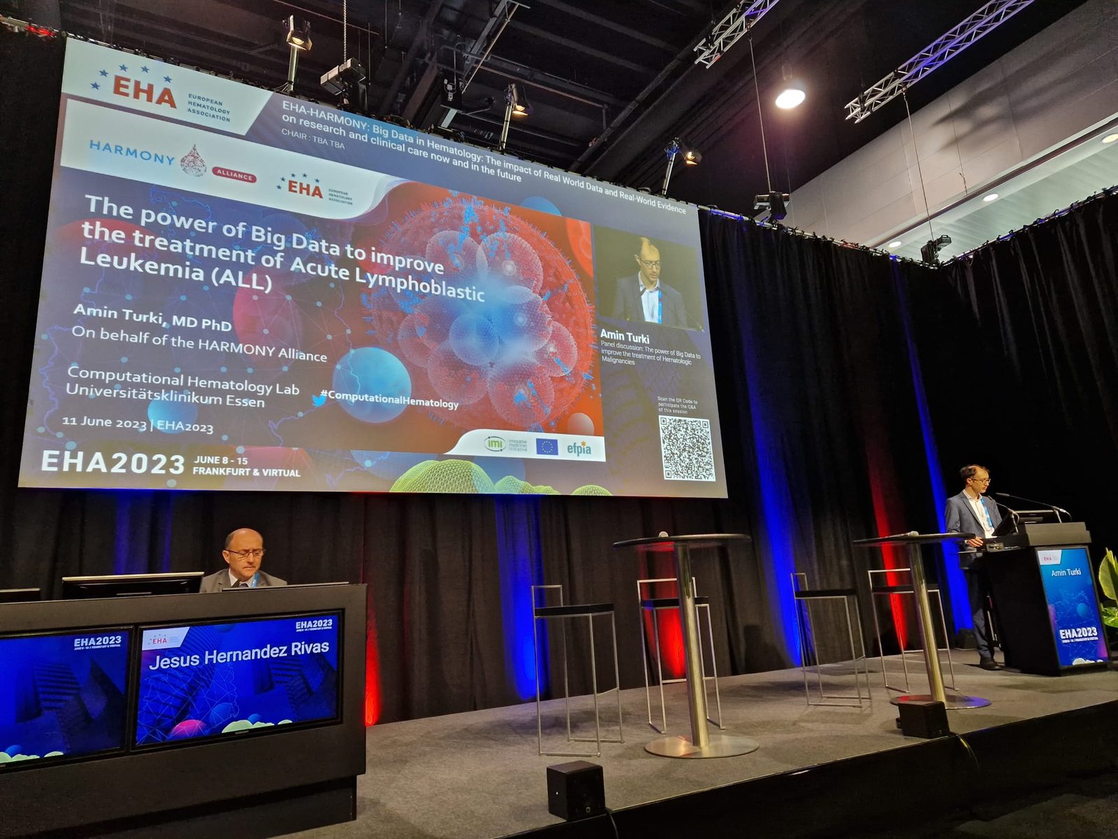 Amin Turki at the EHA 2023 lectern in Frankfurt while a HARMONY Alliance slide on big data and acute lymphoblastic leukemia is on screen.